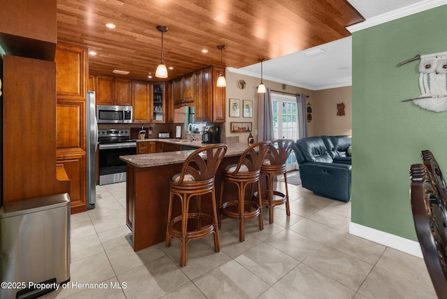 kitchen with pendant lighting, crown molding, appliances with stainless steel finishes, a kitchen bar, and kitchen peninsula