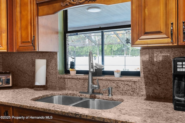 kitchen with sink, light stone counters, and decorative backsplash