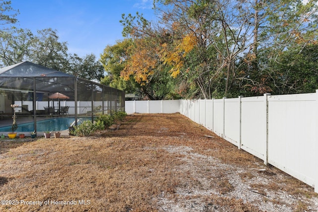 view of yard featuring a fenced in pool and glass enclosure