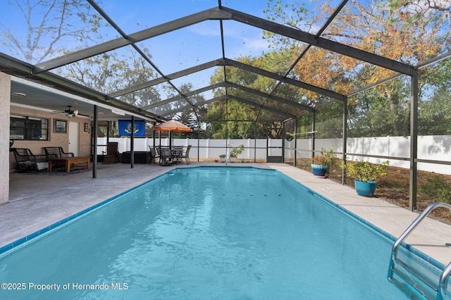 view of pool with a patio, ceiling fan, and glass enclosure