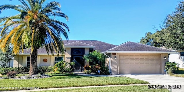 single story home featuring a front yard, concrete driveway, a garage, and stucco siding