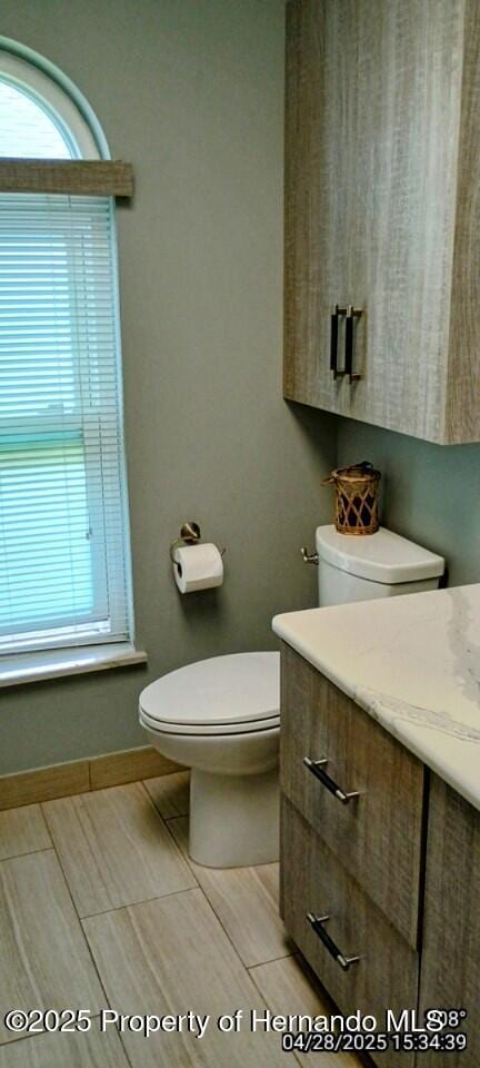 bathroom featuring toilet, vanity, and baseboards