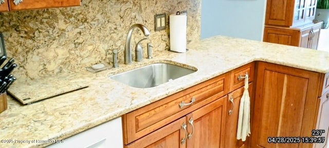 kitchen featuring light stone counters, decorative backsplash, and a sink