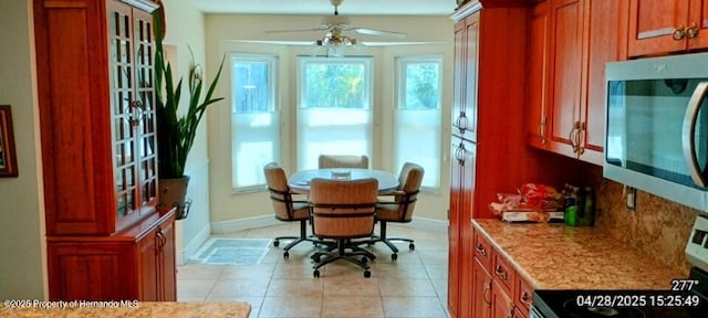 dining area with light tile patterned flooring, ceiling fan, plenty of natural light, and baseboards