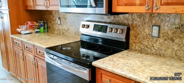 kitchen with tile patterned flooring, appliances with stainless steel finishes, brown cabinetry, and tasteful backsplash