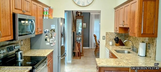 kitchen with light stone countertops, stainless steel appliances, backsplash, a sink, and light tile patterned flooring
