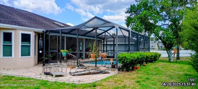 back of house with a patio area, stucco siding, glass enclosure, fence, and a yard