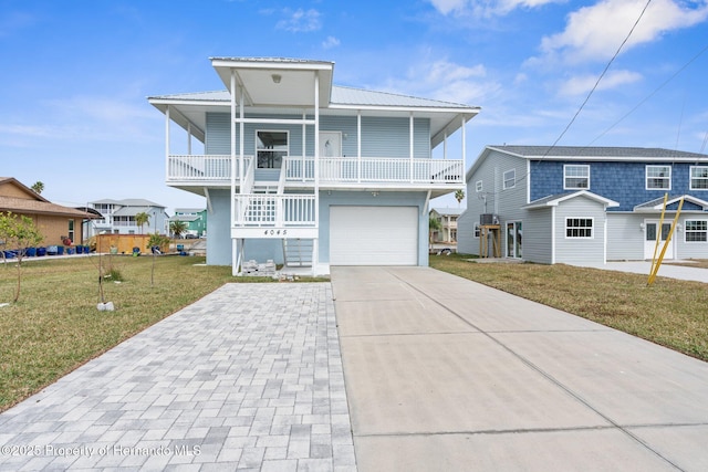 raised beach house featuring a garage, a front yard, and covered porch