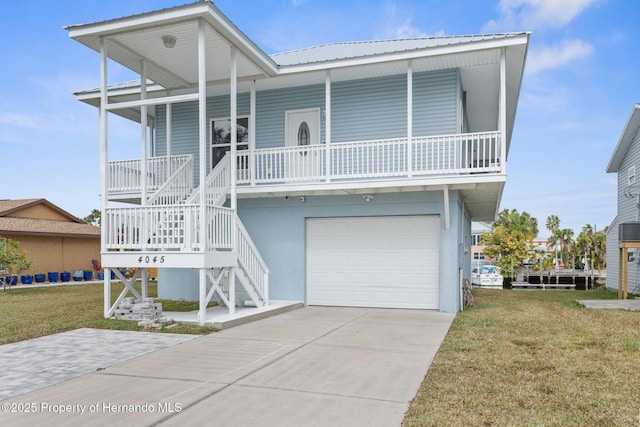 coastal home featuring a porch, a garage, and a front yard