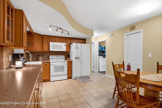 kitchen with sink, white appliances, a textured ceiling, light tile patterned flooring, and washer / dryer