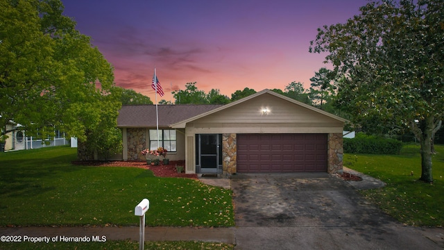 ranch-style house featuring a garage and a lawn