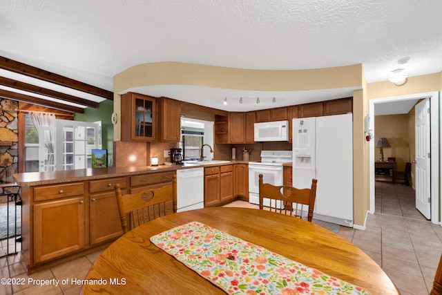 kitchen with sink, a textured ceiling, light tile patterned floors, white appliances, and beam ceiling