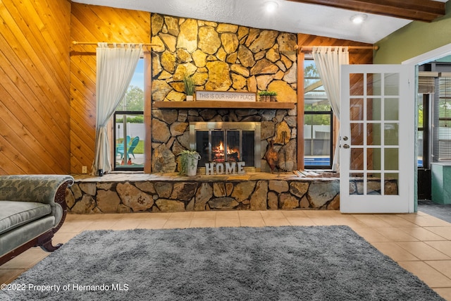 tiled living room with lofted ceiling with beams, a stone fireplace, and wooden walls