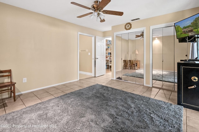 tiled bedroom featuring multiple closets and ceiling fan