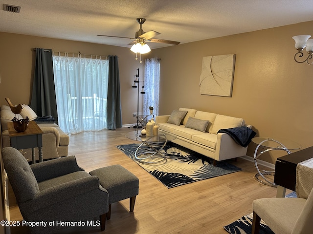 living room with ceiling fan, light hardwood / wood-style flooring, and a textured ceiling