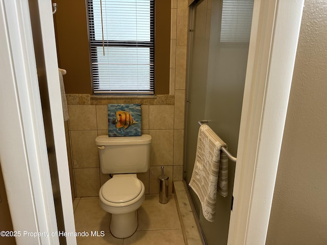 bathroom with tile walls, a shower with door, tile patterned floors, and toilet