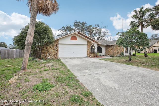 ranch-style home featuring a garage, concrete driveway, stone siding, fence, and a front yard