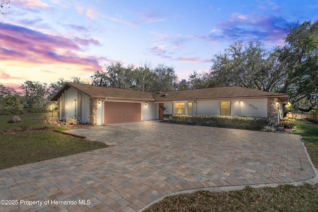 single story home featuring decorative driveway, a garage, and stucco siding