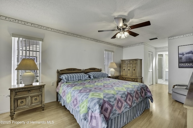 bedroom with ensuite bath, a textured ceiling, and light wood-type flooring