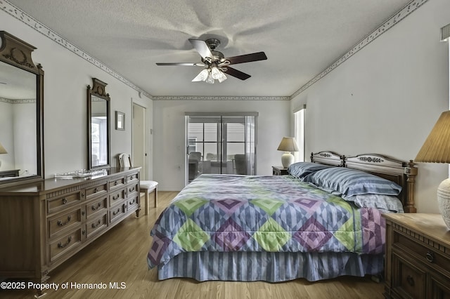 bedroom with hardwood / wood-style flooring, ceiling fan, and a textured ceiling