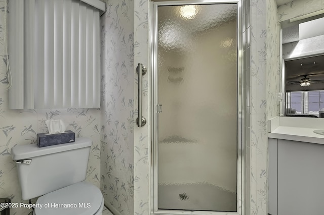 bathroom featuring a shower with door, vanity, and toilet