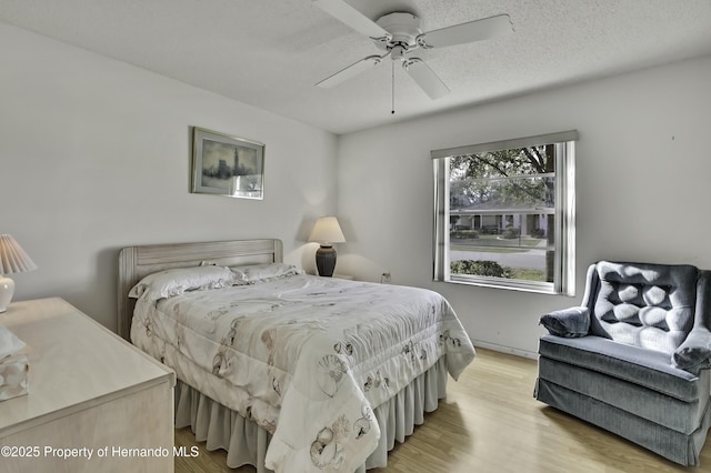 bedroom featuring ceiling fan, light hardwood / wood-style floors, and a textured ceiling