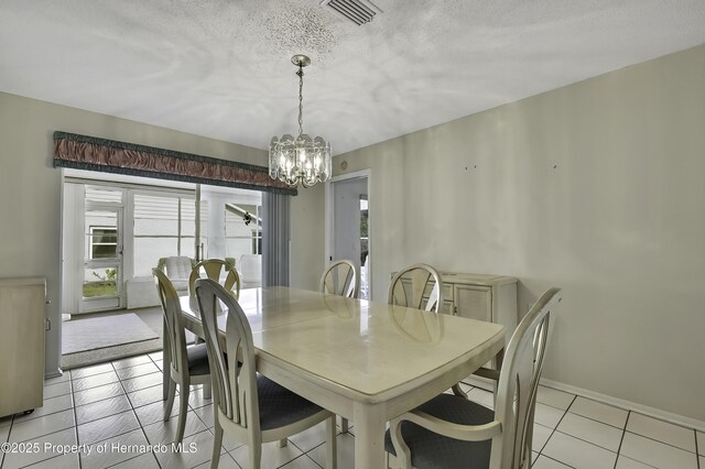 dining area with a textured ceiling, a chandelier, and light tile patterned flooring