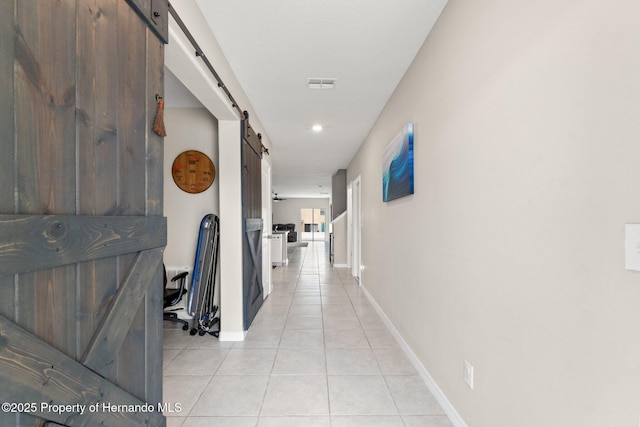 corridor featuring a barn door and light tile patterned floors