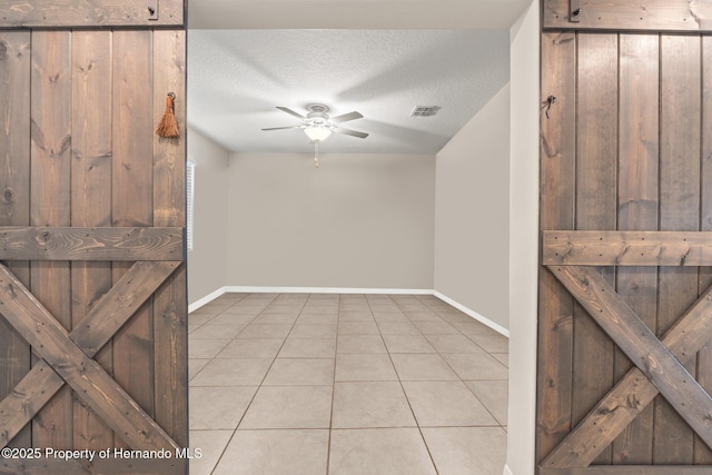 interior space with ceiling fan, a textured ceiling, and light tile patterned floors