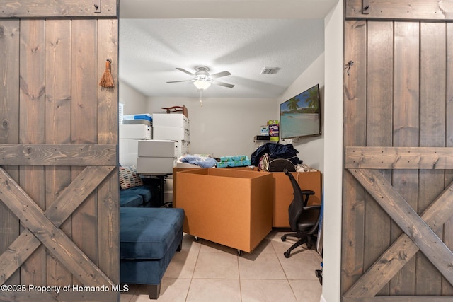 tiled home office featuring ceiling fan, vaulted ceiling, and a textured ceiling