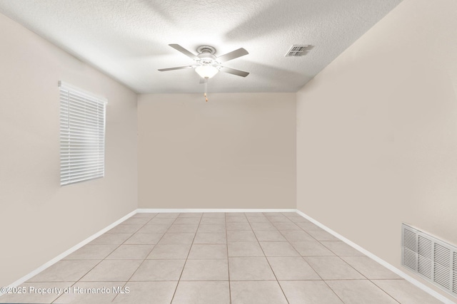 empty room featuring a textured ceiling, ceiling fan, and light tile patterned flooring