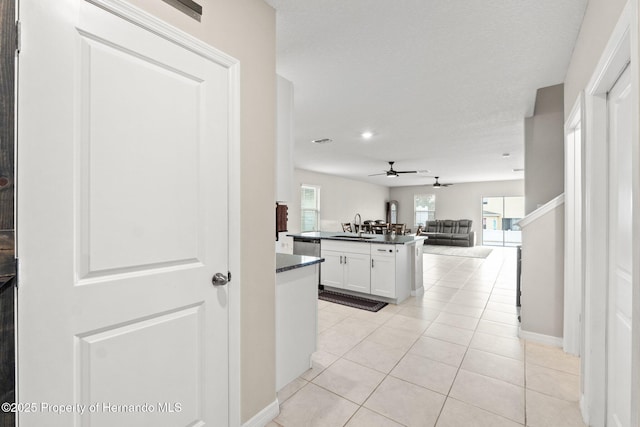 kitchen featuring sink, ceiling fan, white cabinetry, light tile patterned flooring, and stainless steel dishwasher