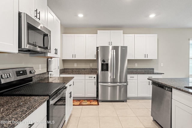 kitchen featuring dark stone countertops, stainless steel appliances, and white cabinets