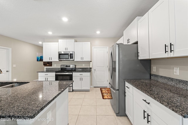 kitchen featuring light tile patterned flooring, sink, dark stone countertops, white cabinets, and stainless steel appliances