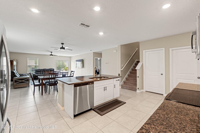 kitchen featuring an island with sink, sink, white cabinets, light tile patterned floors, and stainless steel appliances