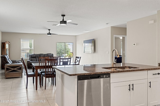 kitchen with sink, white cabinetry, light tile patterned floors, dark stone countertops, and stainless steel dishwasher