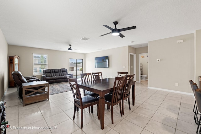 tiled dining space with ceiling fan and a textured ceiling