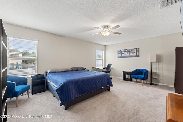 bedroom with ceiling fan, light colored carpet, and a textured ceiling