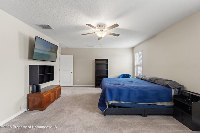 bedroom with a textured ceiling, light colored carpet, and ceiling fan