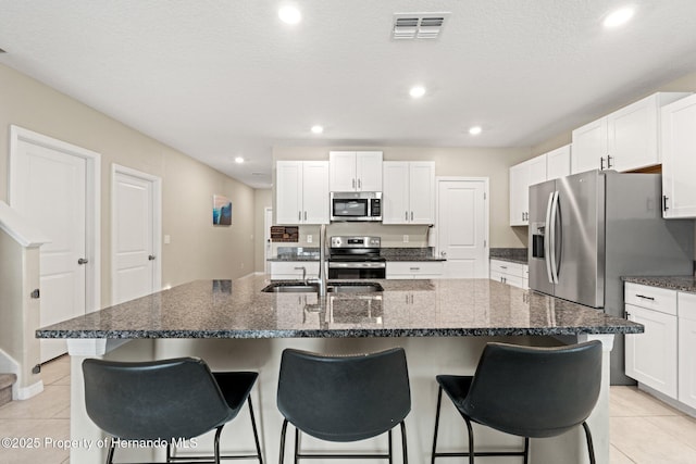 kitchen with a kitchen island with sink, white cabinetry, and appliances with stainless steel finishes