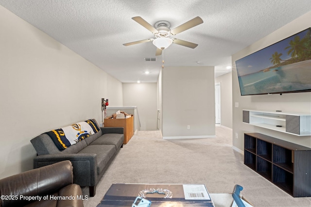 living room with ceiling fan, light carpet, and a textured ceiling