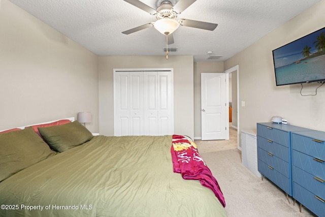 carpeted bedroom featuring ceiling fan, a textured ceiling, and a closet