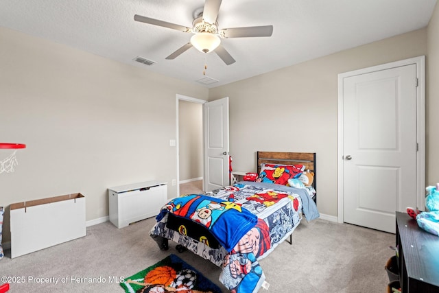 bedroom with ceiling fan, light carpet, and a textured ceiling