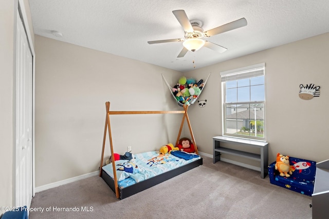 bedroom with ceiling fan, carpet flooring, and a textured ceiling