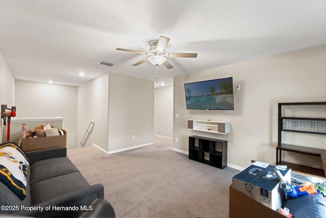 living room featuring ceiling fan, light carpet, and a textured ceiling