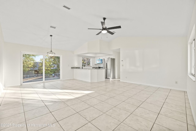 unfurnished living room with vaulted ceiling, ceiling fan with notable chandelier, and light tile patterned floors