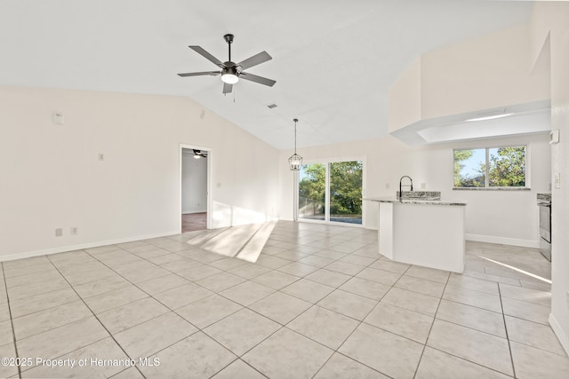 unfurnished living room featuring ceiling fan with notable chandelier, light tile patterned flooring, vaulted ceiling, and a wealth of natural light