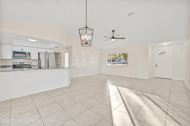 unfurnished living room with lofted ceiling, light tile patterned floors, and ceiling fan with notable chandelier