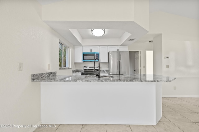 kitchen featuring kitchen peninsula, white cabinetry, a tray ceiling, stainless steel appliances, and light stone countertops