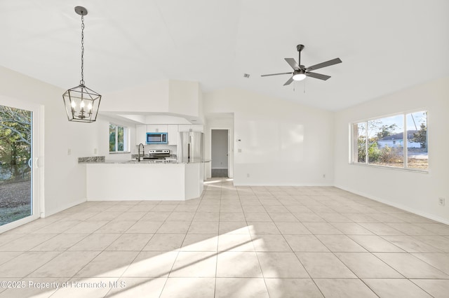 unfurnished living room featuring lofted ceiling, sink, ceiling fan with notable chandelier, and light tile patterned flooring